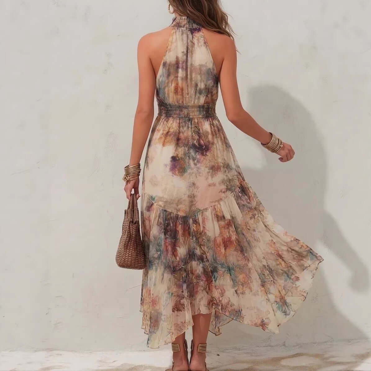 Back view of a woman wearing a lightweight womens halter neck printed dress with a flowing skirt.