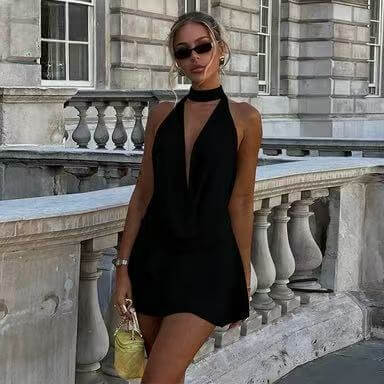 Stylish model in a backless halter neck dress posing confidently outdoors.